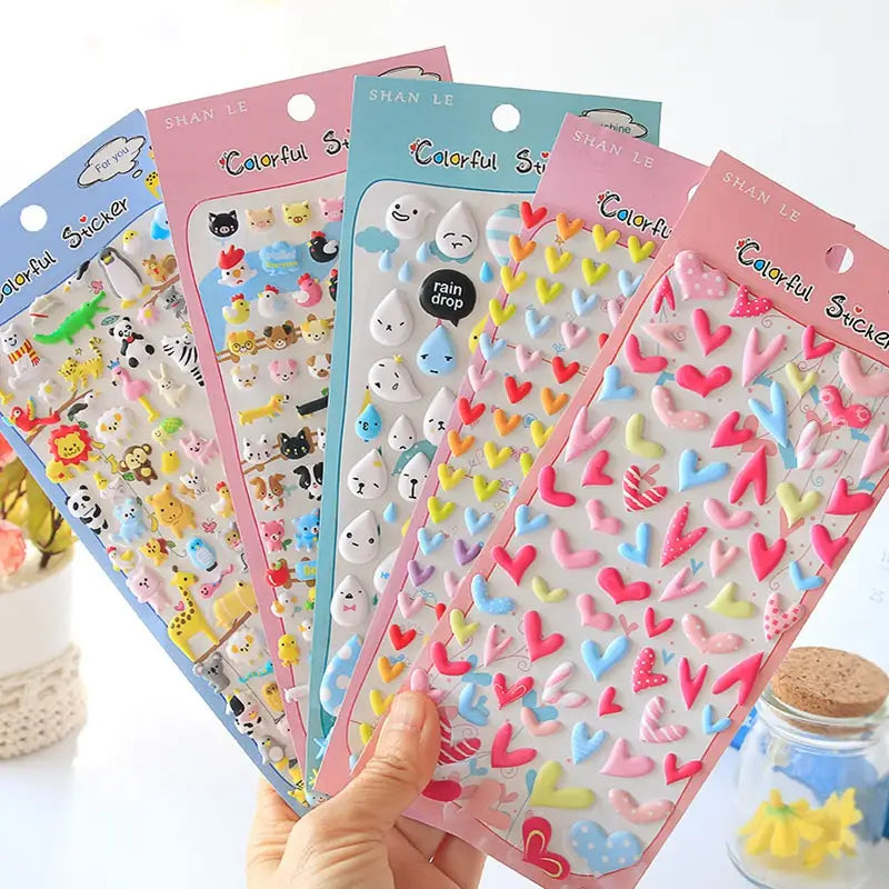 Handheld display of multi-theme "Colorful Sticker" 3D puffy sticker set, showing zoo animals, raindrops, and heart designs.