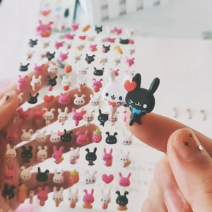 Handheld display of transparent rabbit 3D bubble stickers, showing cute black/white/pink bunny designs with strawberry/carrot elements