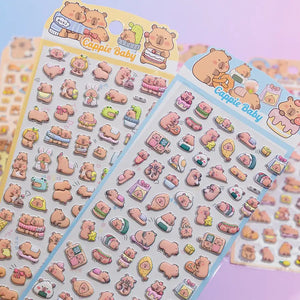 Handheld display of 3D puffy sticker sheets with cute Capybara (Cappie Baby) designs, self-adhesive PVC epoxy stickers for DIY crafts and stationery decoration