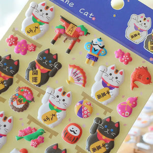 Close-up of 3D puffy Fortune Cat stickers with Japanese-style elements (torii gate, daruma, koi fish, etc.), perfect for DIY phone case decoration.