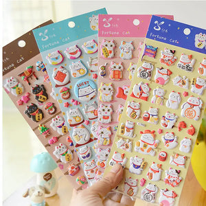 Display of multi-color "Fortune Cat" 3D puffy sticker set, showing cute lucky cat designs in light blue, pink, blue, and brown themes.