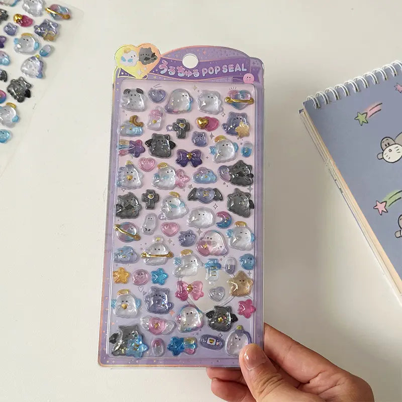 Handheld display of 3D crystal puffy sticker sheets with cute ghost and angel character designs, in pastel purple and white color schemes