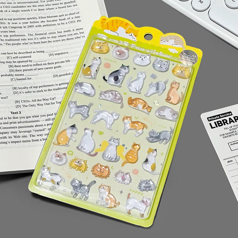 A yellow retail sheet of Nekoni 3D glossy drop-seal stickers featuring cute derpy cartoon cats in various sitting, stretching, and laying poses for DIY crafts.
