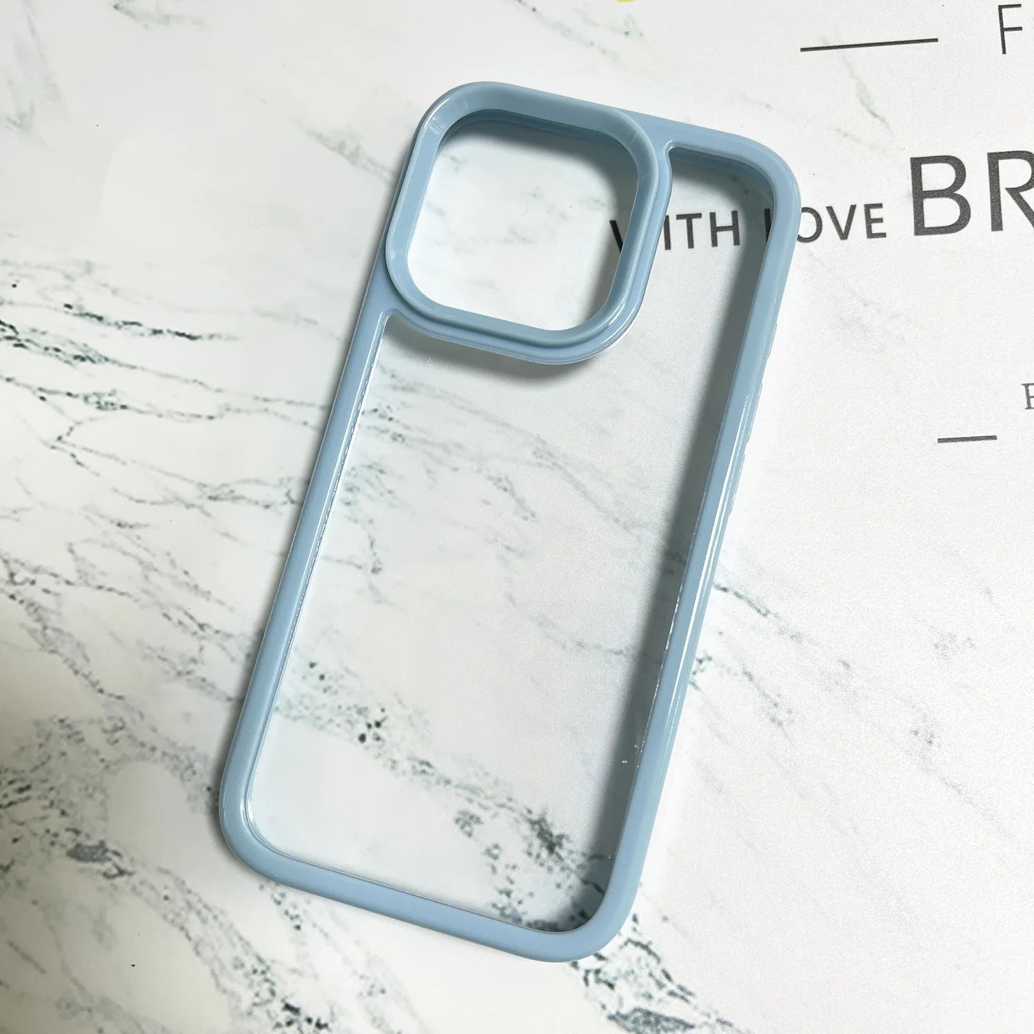 A premium minimalist hybrid phone case featuring a pastel light blue shockproof wide border, a raised camera protection frame, and a crystal clear back panel.