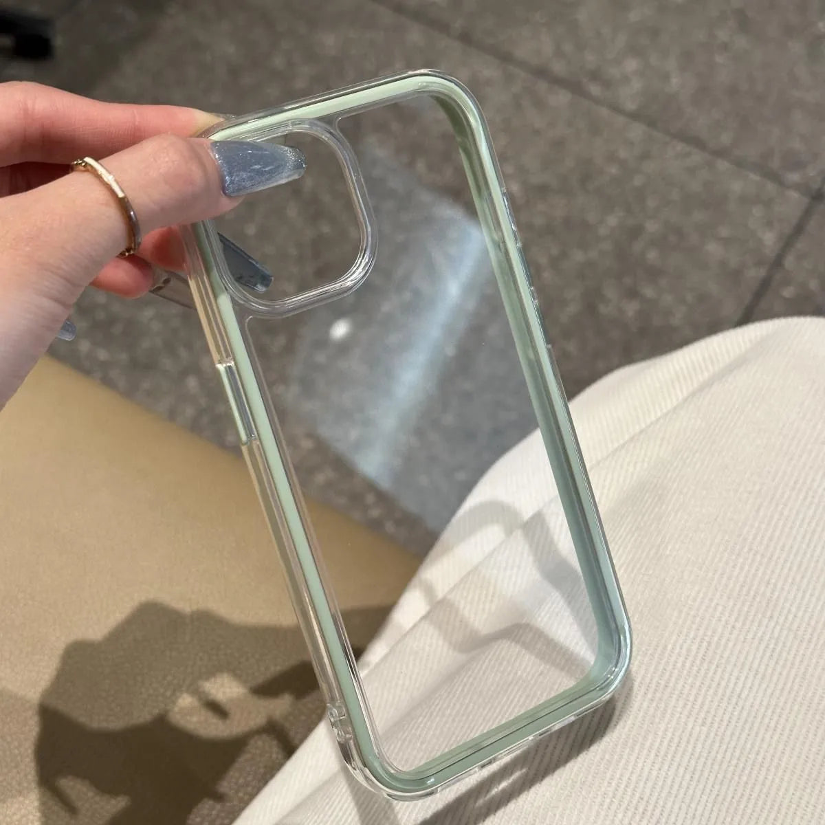 A minimalist hybrid protective phone case with a clear mint green accent frame and a crystal clear transparent back panel, held in hand.