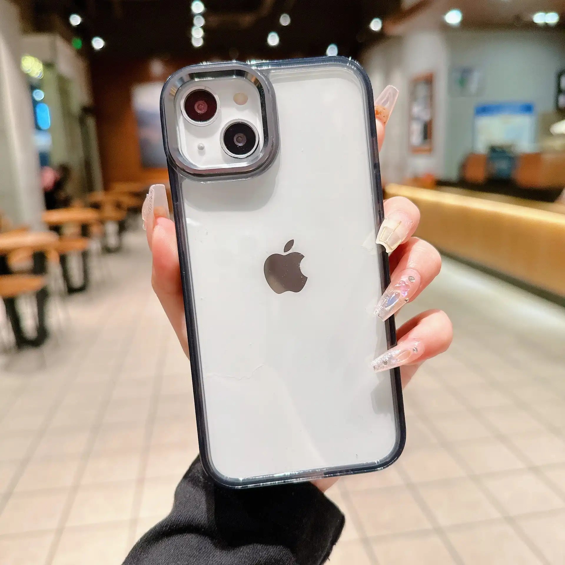 A premium semi-translucent black hybrid phone case featuring an elevated matte metallic camera protective frame and clear frosted back, held in hand.