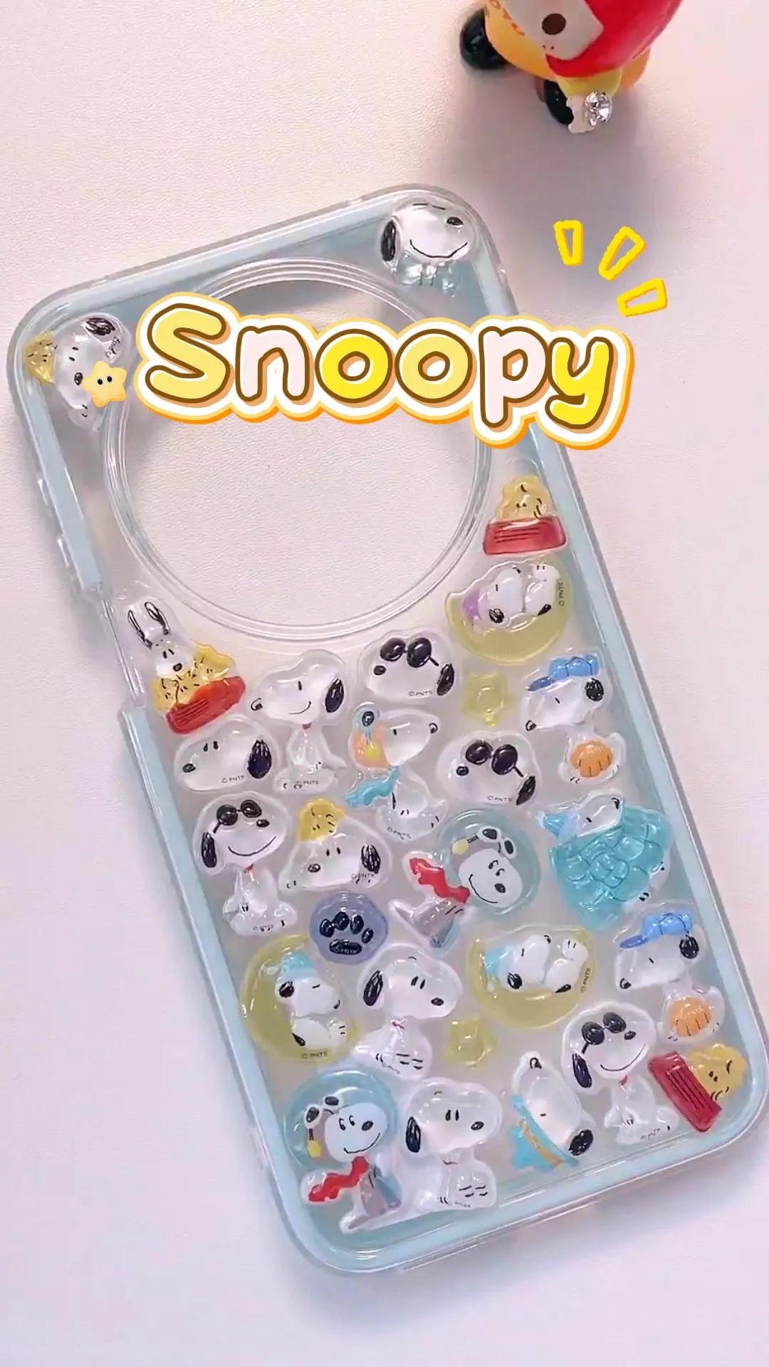 Handcrafted clear ice blue phone case filled with a dense 3D collage of glossy, holographic aurora bubble ghost bird charms reflecting colorful rainbow light.