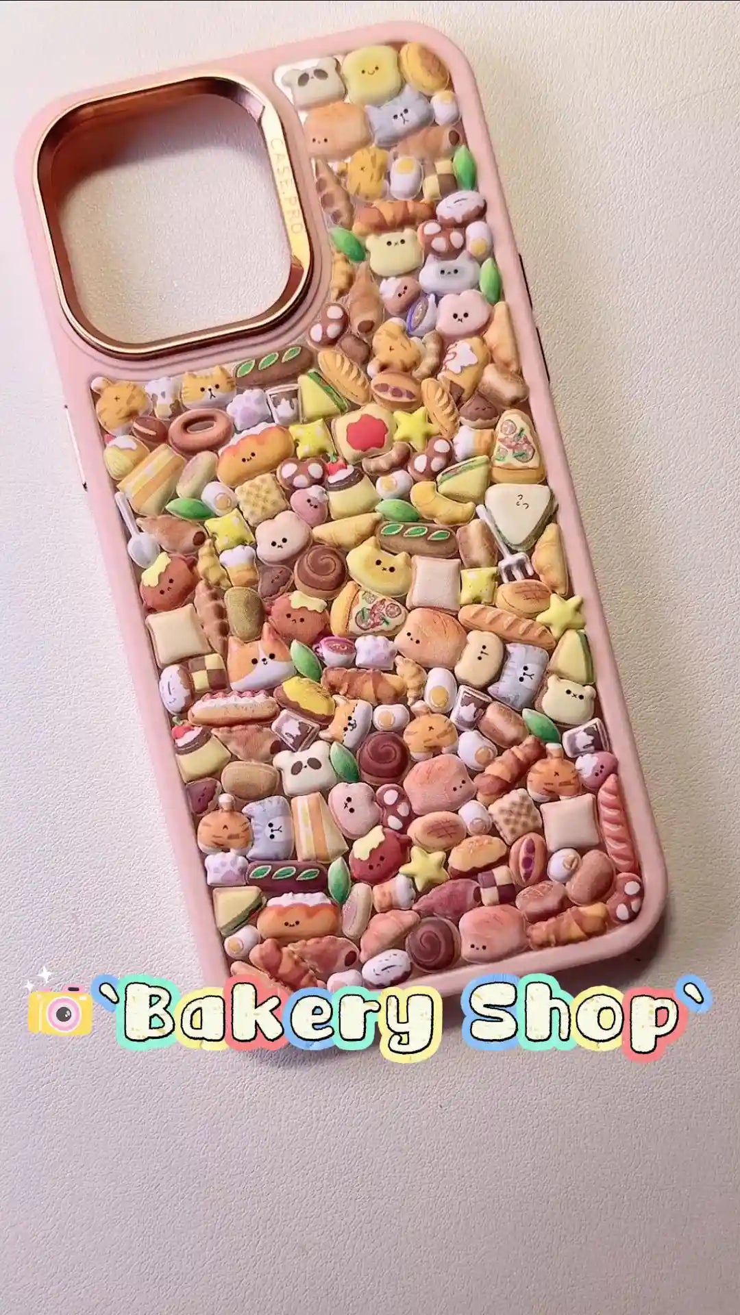 Handcrafted clear phone case with a sand pink border and luxury rose gold camera rim, densely filled with a 3D collage of glossy, golden-brown cartoon sandwiches, croissants, and bread loaves.