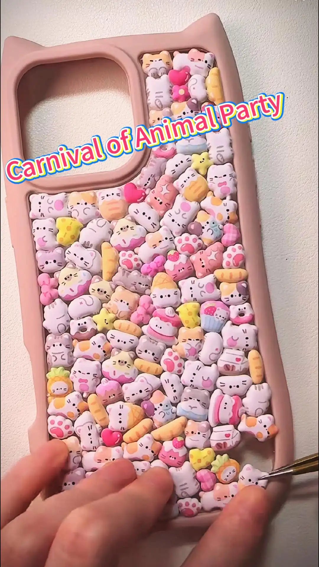 Handcrafted phone case with a pastel pink cat-ear shaped border, densely filled with a 3D collage of glossy cartoon kitten charms, pink donuts, and mini cat paw details.