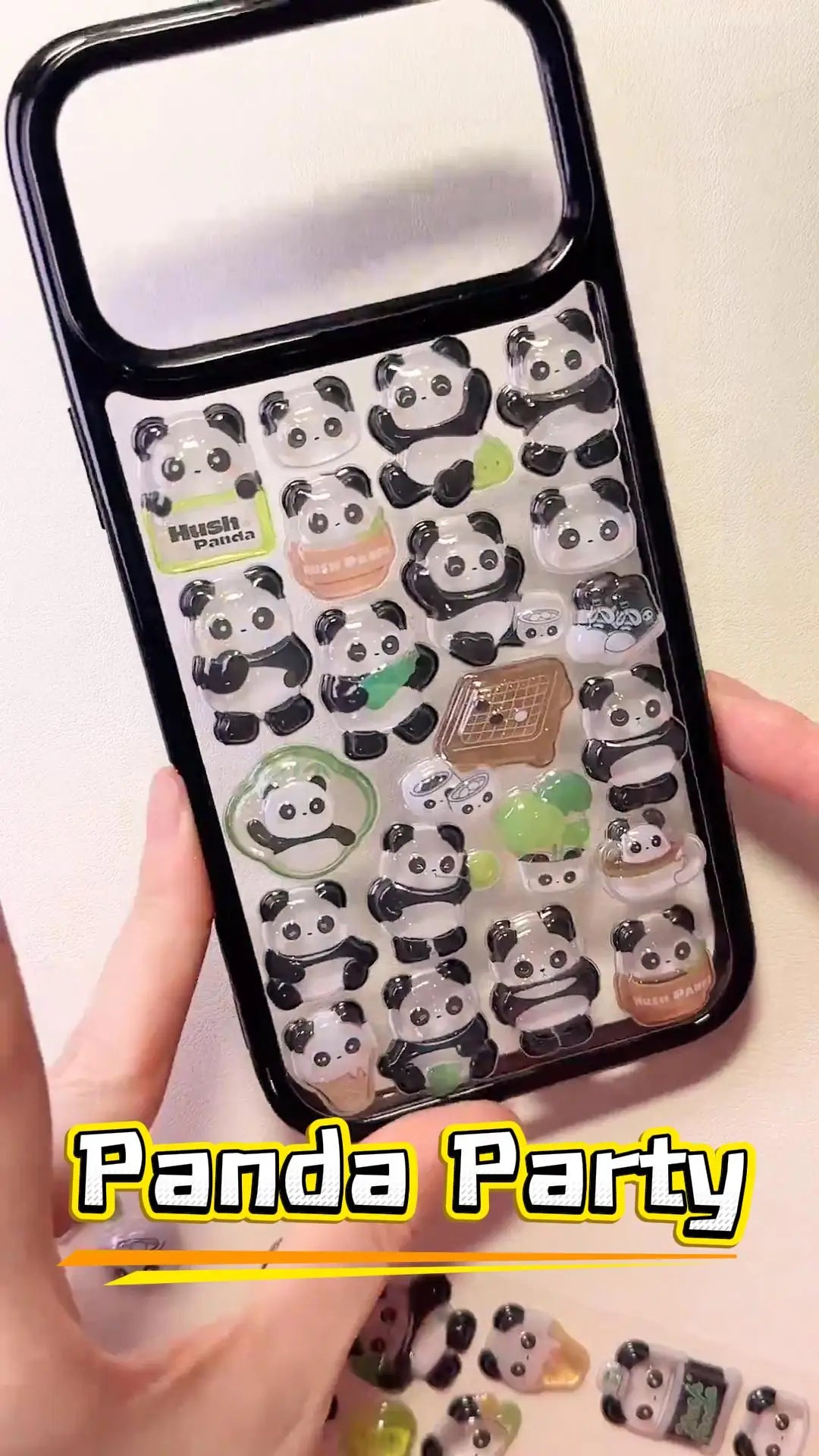 Handcrafted clear phone case with a sleek black border, densely filled with a 3D collage of glossy, crystal-like cartoon panda charms eating bamboo and relaxing.