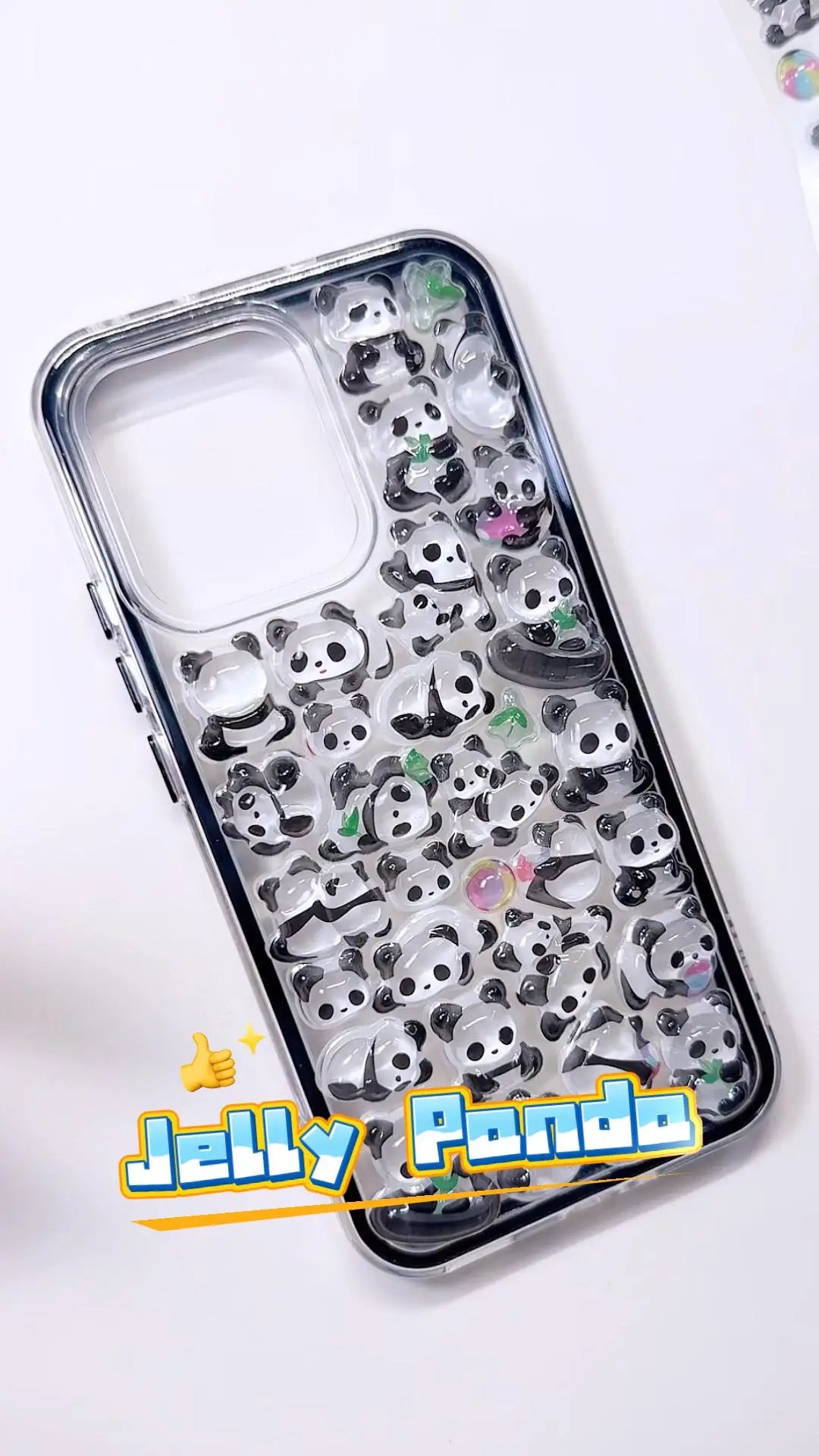 Handcrafted clear phone case with a sleek black bumper frame, densely decorated with a 3D collage of glossy, holographic aurora giant panda charms and tiny green bamboo leaves.