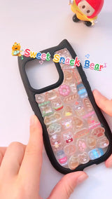 Handcrafted phone case with a matte black cat-ear shaped border, densely filled with a 3D collage of glossy, amber caramel cartoon chef bear charms, miniature croissants, and donuts.