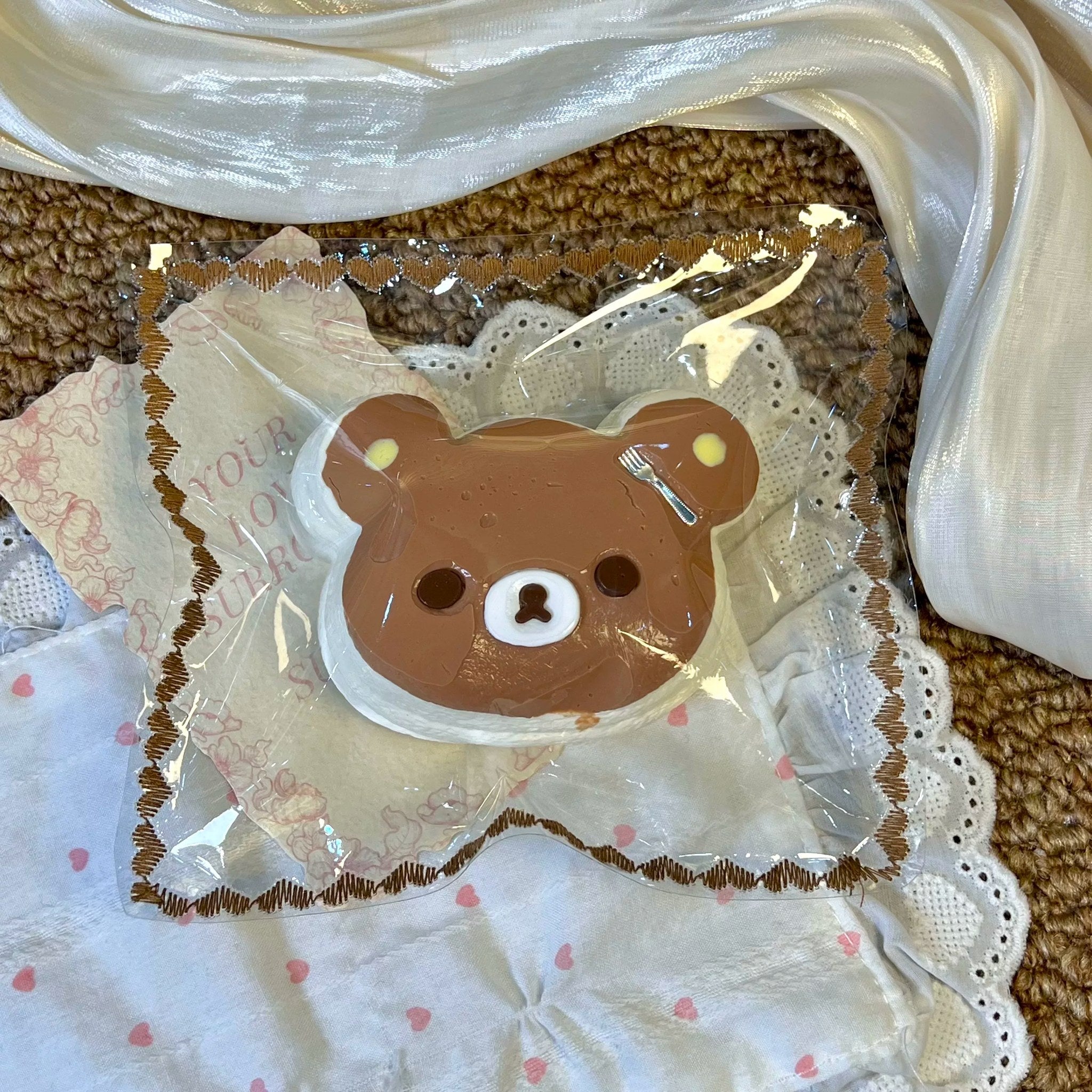 Brown bear-face cake-shaped squishy in clear packaging.