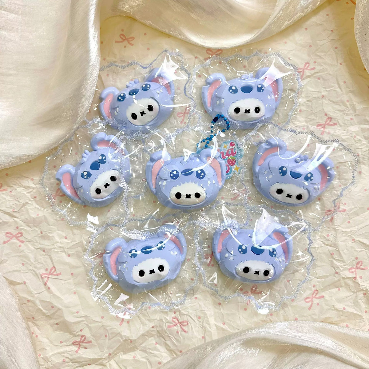 Several white bunny faces wearing blue character hoods, each in clear packaging.