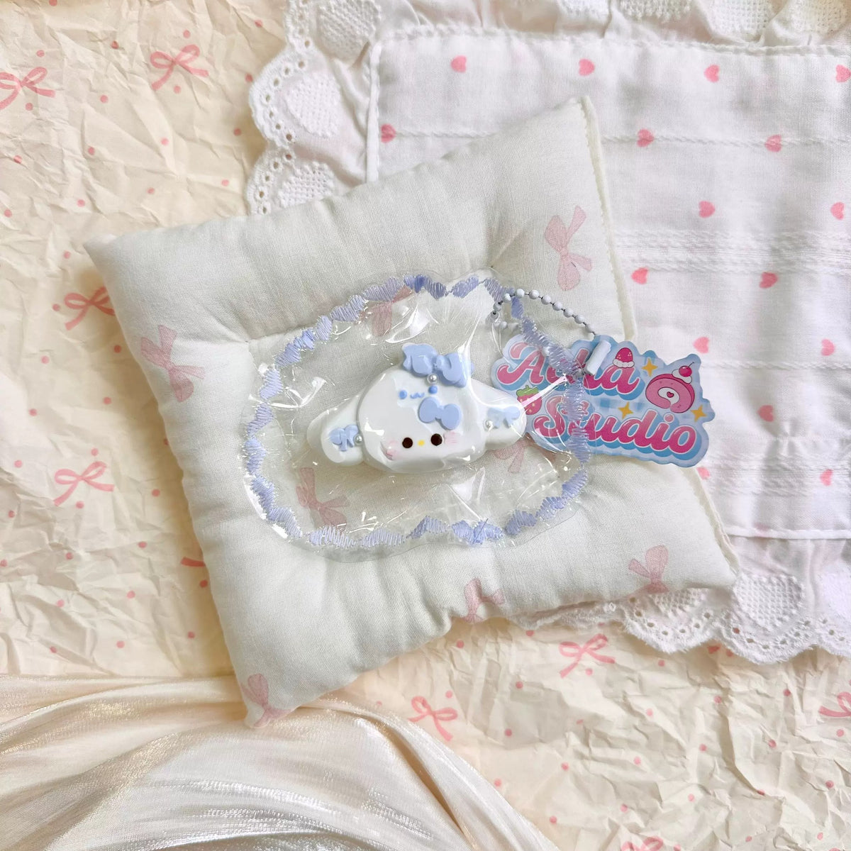 White cat-shaped squishy wearing a pale blue long-eared hood in clear packaging.