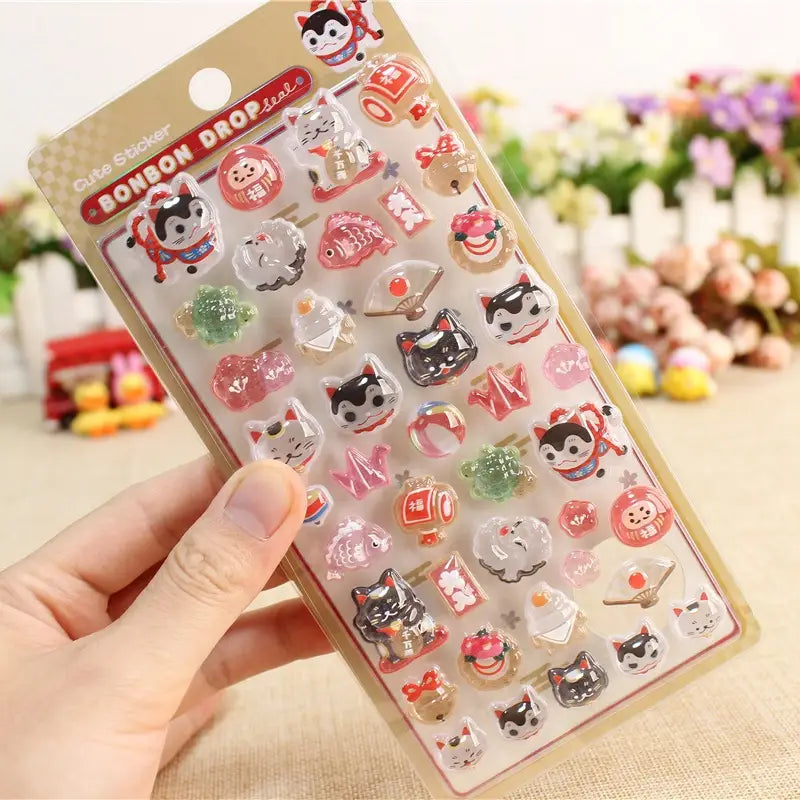 BONBON DROP" cute kawaii sticker sheet with glossy lucky cat, daruma, and koi fish designs, perfect for DIY phone case decoration.