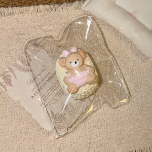 Toast-shaped squishy with a knit-like texture, bear figure and pink bow in clear packaging.