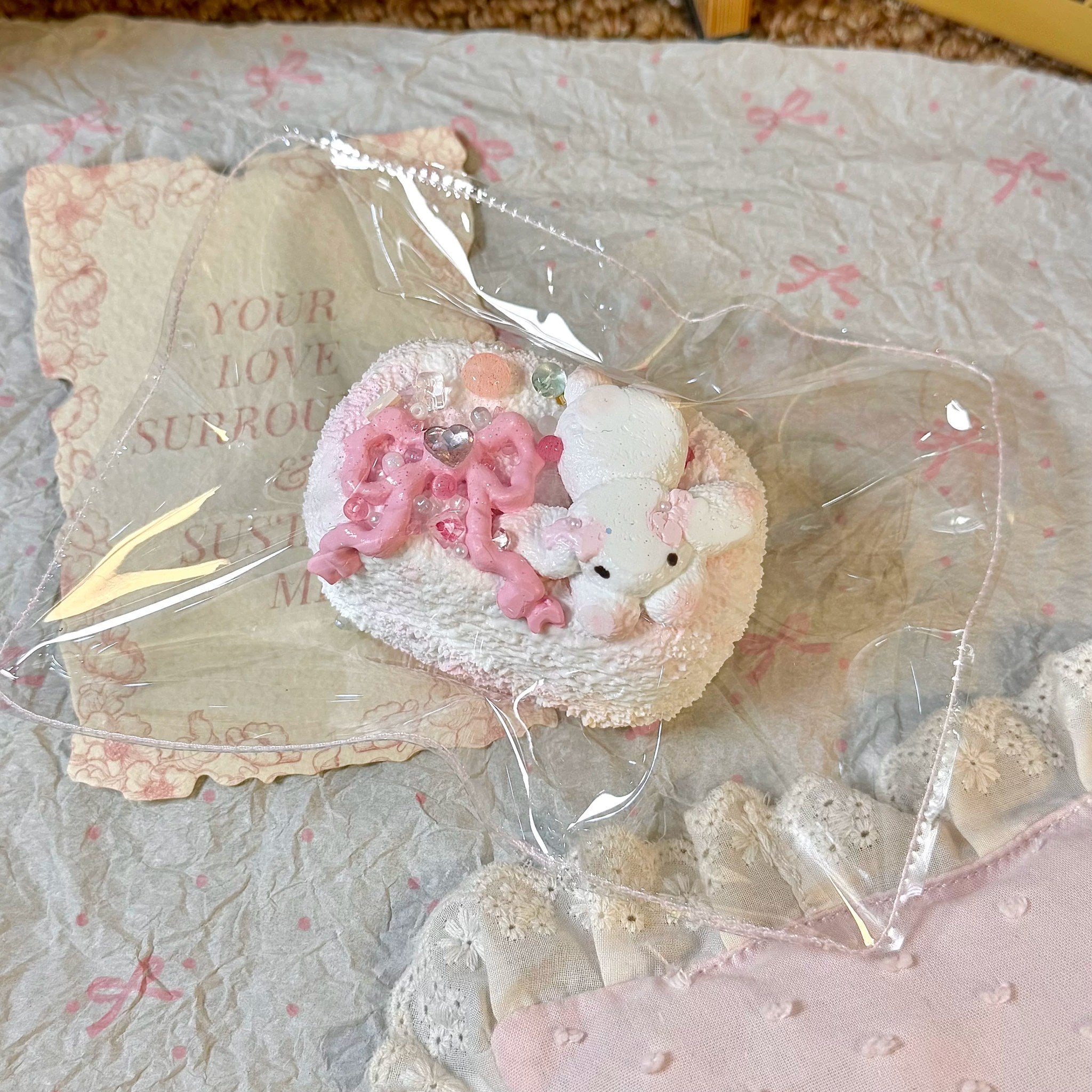 Toast-shaped squishy topped with a white bunny and pink bows in clear packaging.