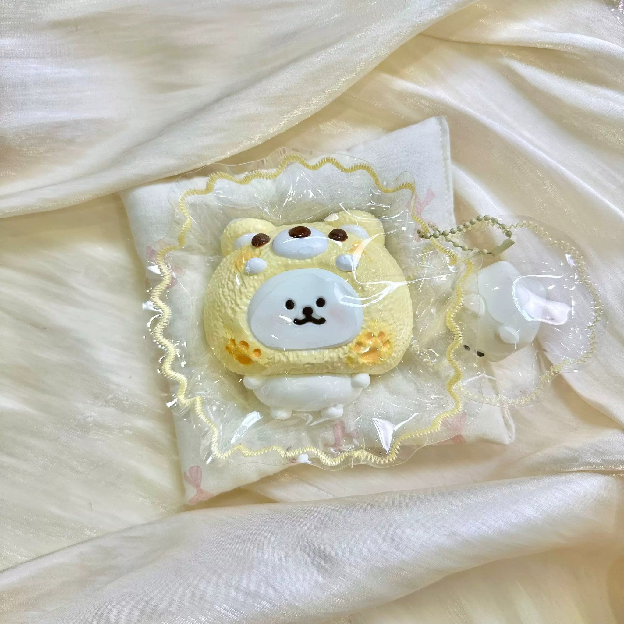 White bear face inside a yellow cat hood in clear packaging.