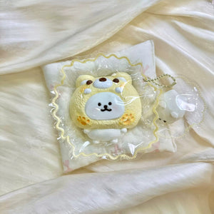 White bear face inside a yellow cat hood in clear packaging.