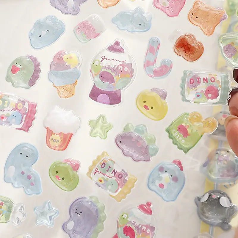 Close-up shot of 3D puffy stickers with dinosaur, gumball machine, and candy packaging designs, highlighting the transparent iridescent texture and cute details
