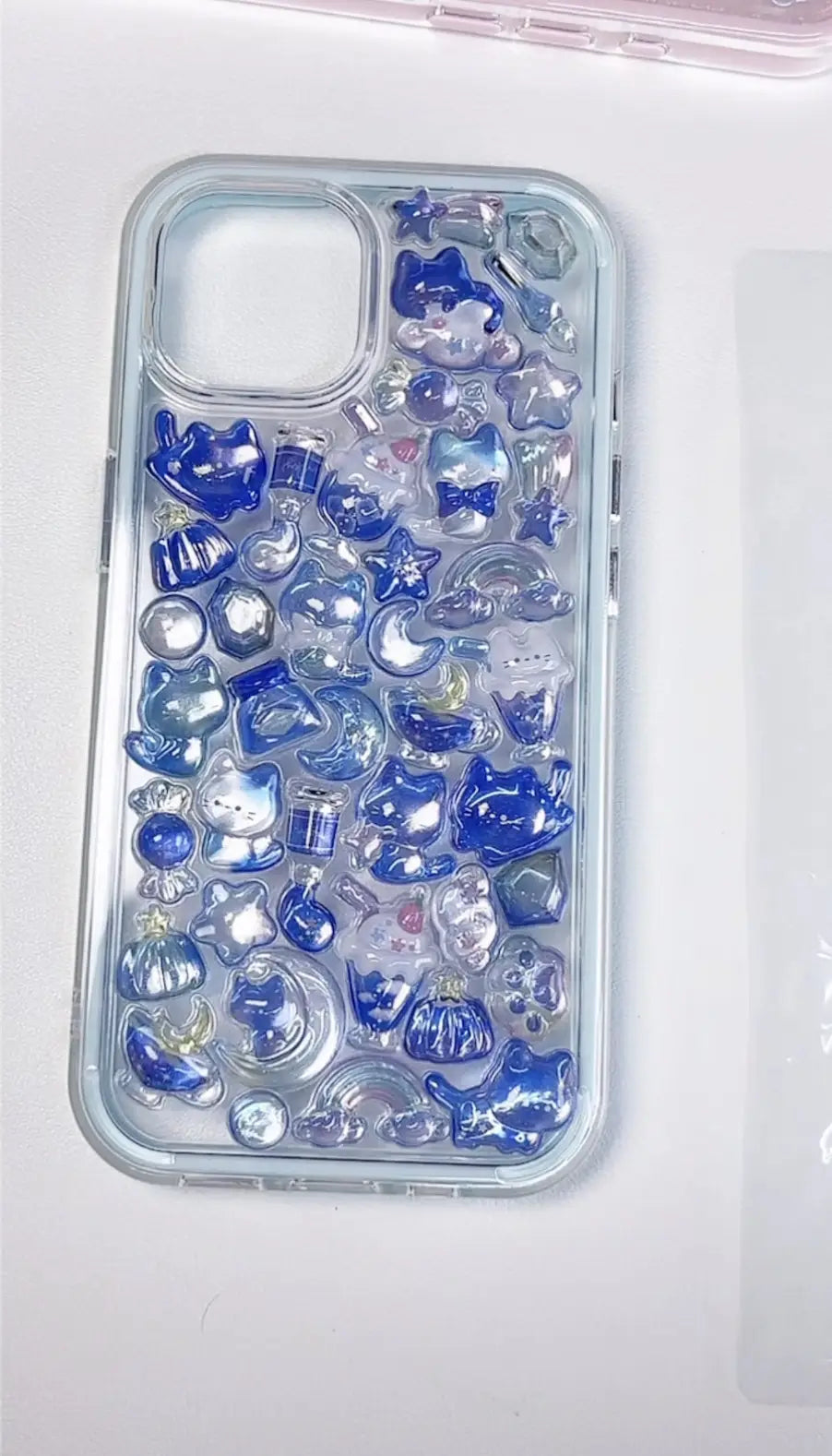 Finished DIY iPhone case with light blue gradient frame, decorated with glossy Bonbon Drop blue starry cat, moon, and cute character stickers, creating a dreamy celestial aesthetic.