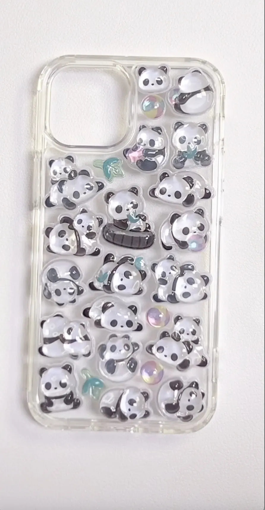 Finished DIY clear iPhone case decorated with glossy Bonbon Drop jelly panda stickers, featuring cute panda and bamboo designs with iridescent details.