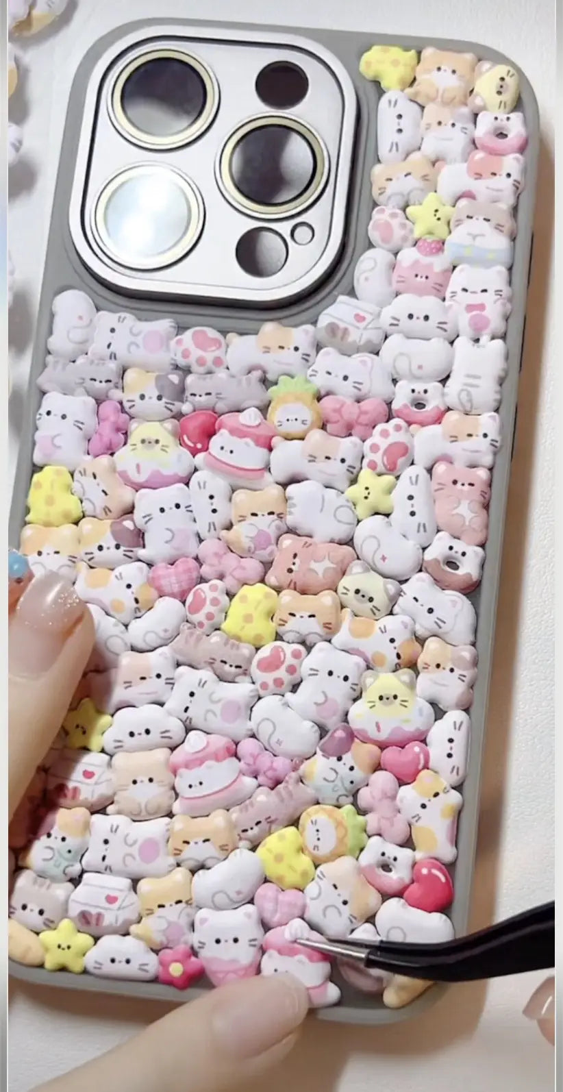 Finished DIY iPhone case with gray frame, decorated with dense mini cute cat and animal stickers, featuring a soft pastel kawaii aesthetic.