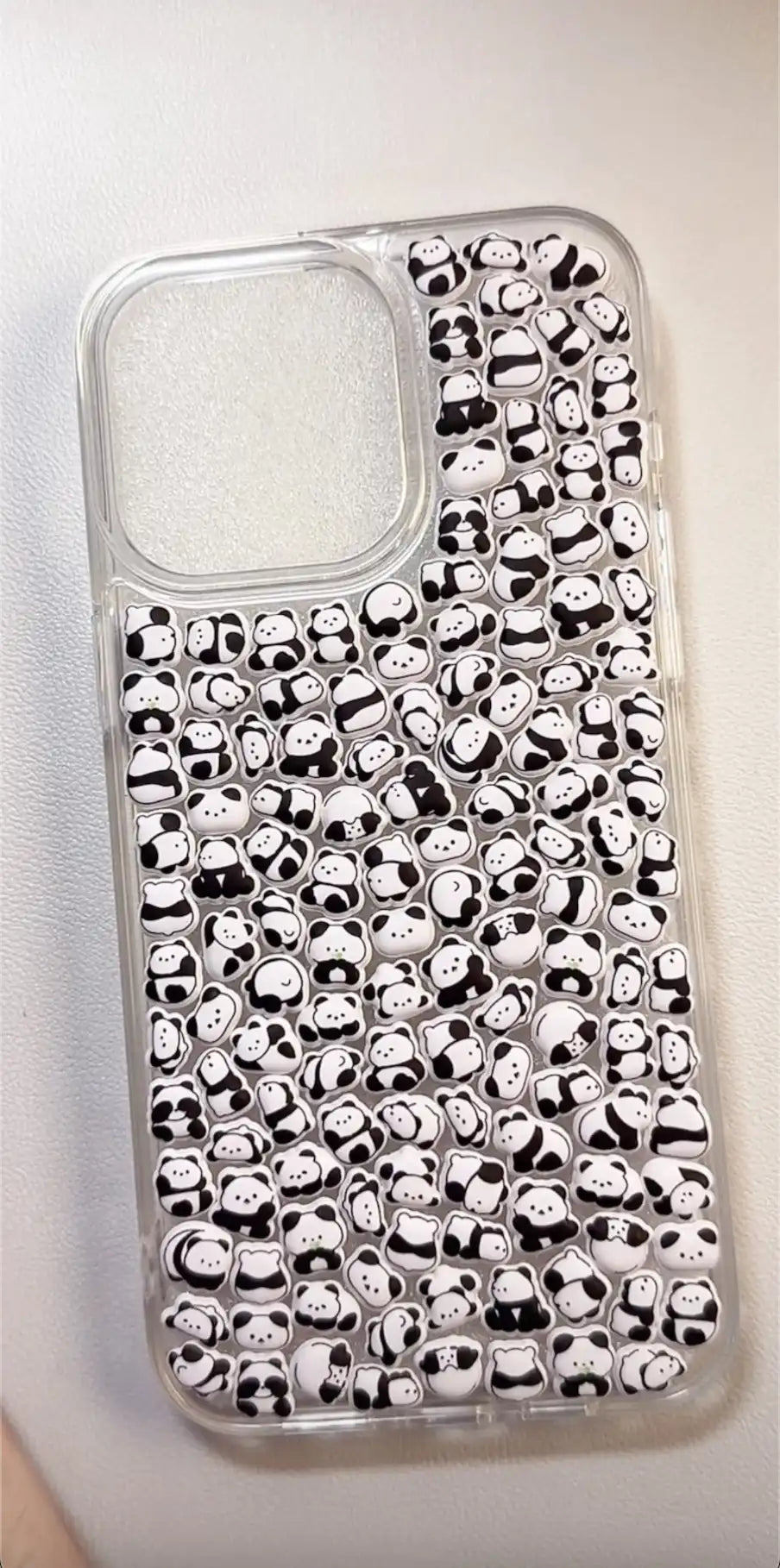Finished DIY clear iPhone case decorated with dense mini panda stickers, featuring a cute minimalist black and white panda aesthetic.