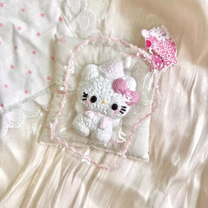 White textured cat-shaped squishy with a pink bow in clear packaging.
