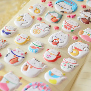 Close-up of 3D puffy Fortune Cat stickers with cute designs and lucky symbols, perfect for DIY phone case decoration.