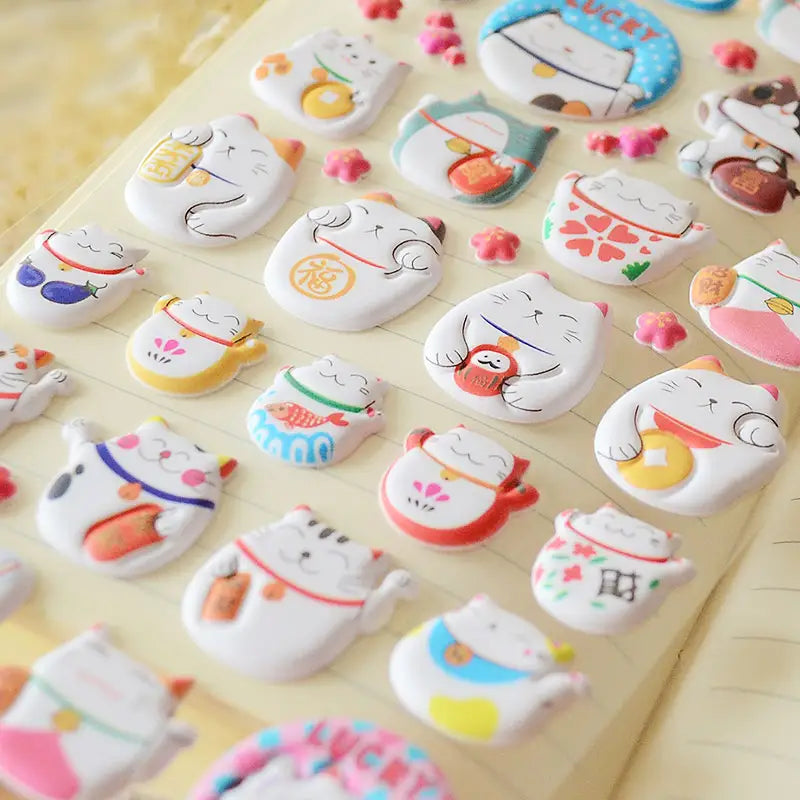 Close-up of 3D puffy Fortune Cat stickers with cute designs and lucky symbols, perfect for DIY phone case decoration.