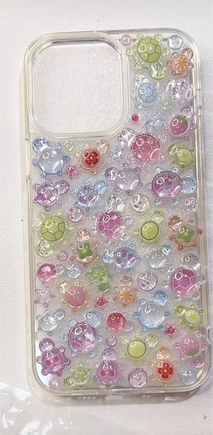 Final look of a handmade DIY phone case covered in rainbow-colored 3D resin turtles and ocean-themed charms.