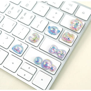 Decorative display of 3D iridescent crystal stickers used for keyboard DIY, featuring cute pet and bow designs with holographic effects