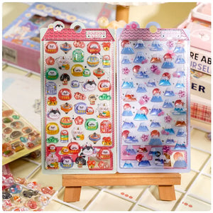 Collection of 3D crystal puffy sticker sheets with adorable Japanese pet designs (daruma, sushi, mount fuji), in red and blue pastel color schemes