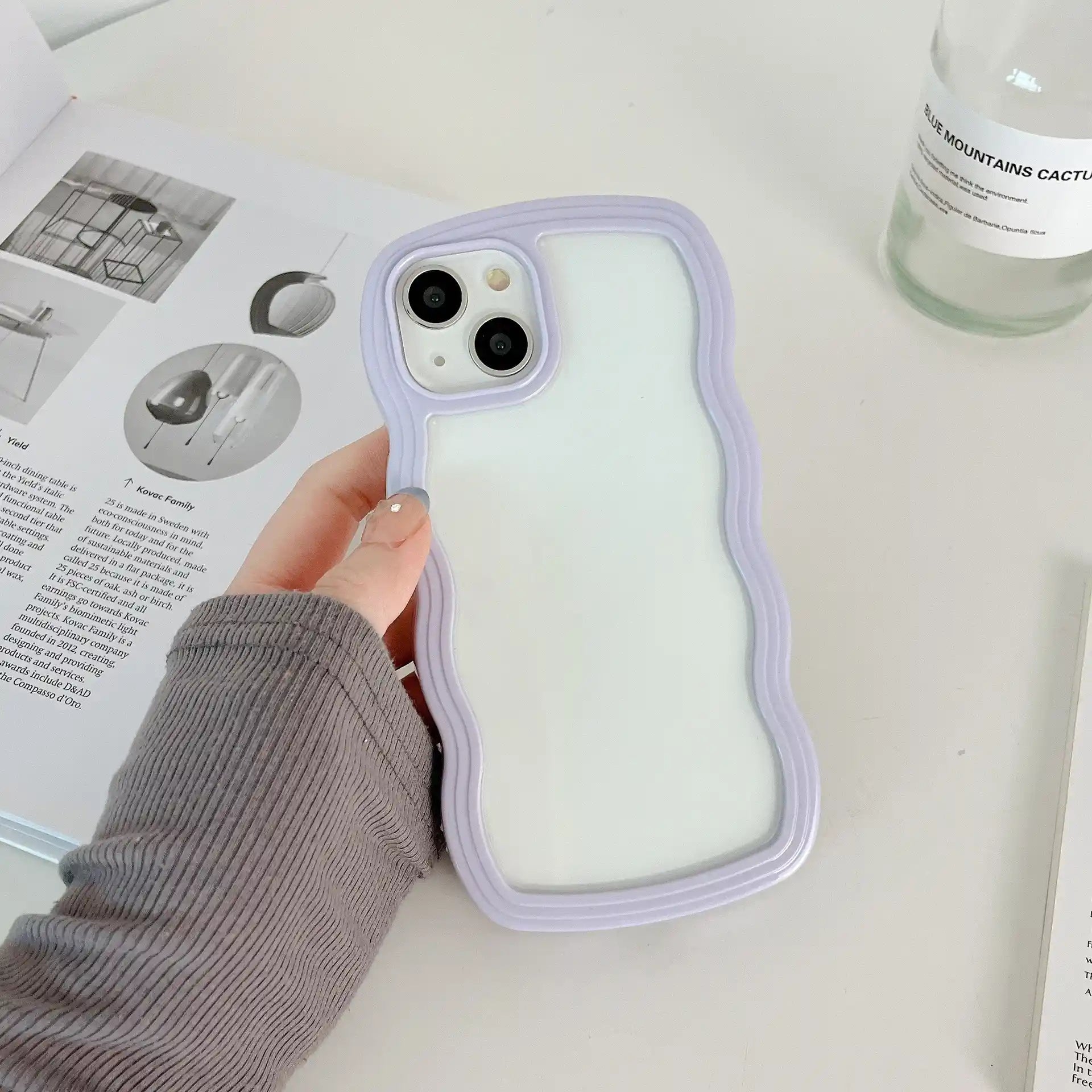 A minimalist hybrid protective phone case with a soft pastel lavender purple border frame and a crystal clear transparent back panel, held in hand.