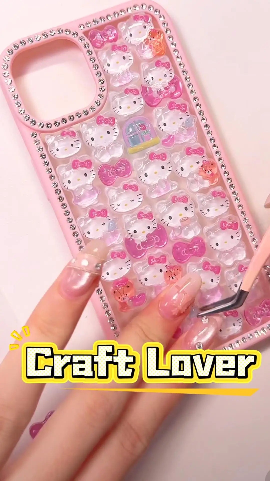 Handcrafted pastel pink phone case fully lined with sparkling diamond rhinestones, filled with a dense 3D collage of clear, glossy Hello Kitty charms.