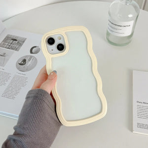 Minimalist light pastel yellow wavy frame phone case with a clear translucent back, held in hand over a desk setup.