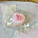 Pink heart-shaped pastry squishy with a textured surface in clear packaging.
