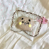 Round tan bun-shaped squishy with yellow cheeks in clear packaging.