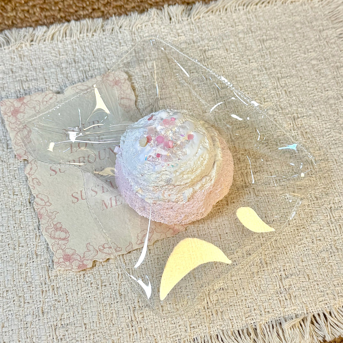 Pastel ice-cream-shaped squishy with a white swirl and pink decorations in clear packaging.