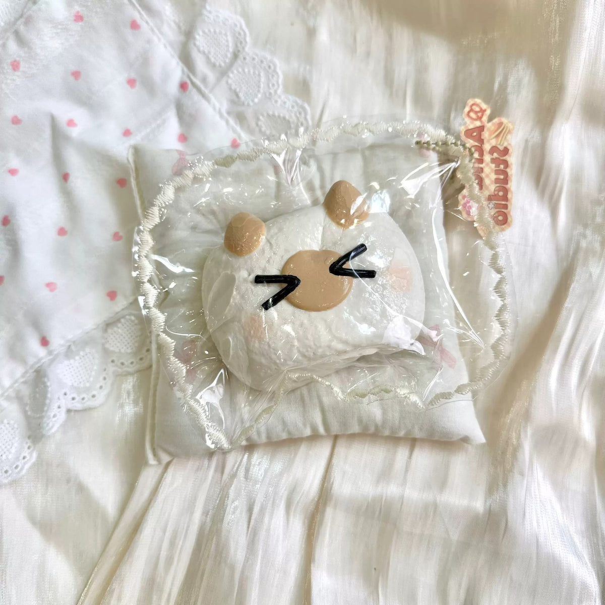 White bun-shaped squishy with tan details and a winking face in clear packaging.