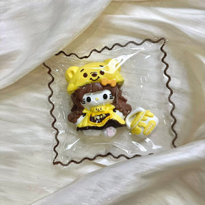 Cat character wearing a yellow bear hood and brown outfit in clear packaging.